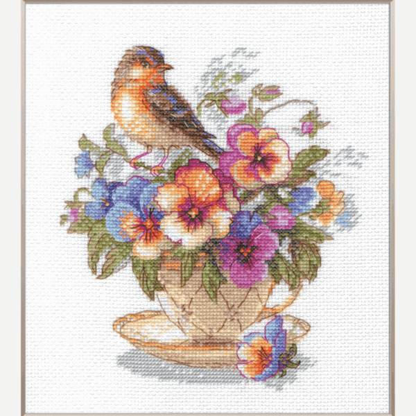 A completed cross-stitch of a small brown bird perched on a teacup filled with colorful pansies in shades of purple, blue, orange, and yellow, stitched on white Aida fabric.
