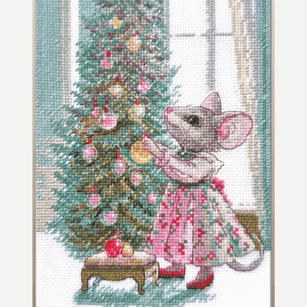 A completed cross-stitch of a mouse in a festive dress decorating a Christmas tree with ornaments, stitched in warm reds, greens, and golds on white Aida fabric.