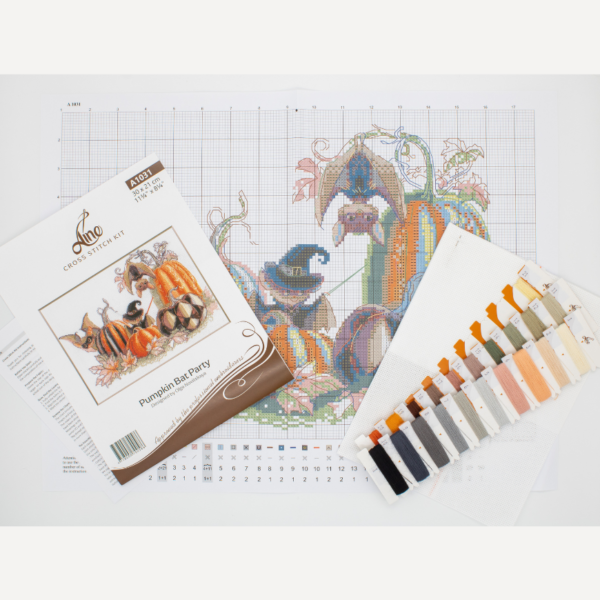 A completed cross-stitch of bats and pumpkins in a Halloween theme, with striped and checkered pumpkins, autumn leaves, and a bat in a witch hat holding a wand.