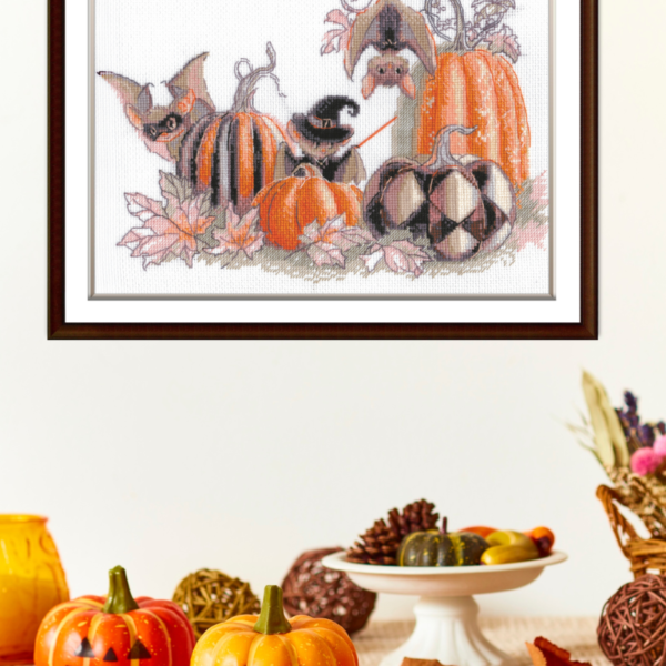 A completed cross-stitch of bats and pumpkins in a Halloween theme, with striped and checkered pumpkins, autumn leaves, and a bat in a witch hat holding a wand.