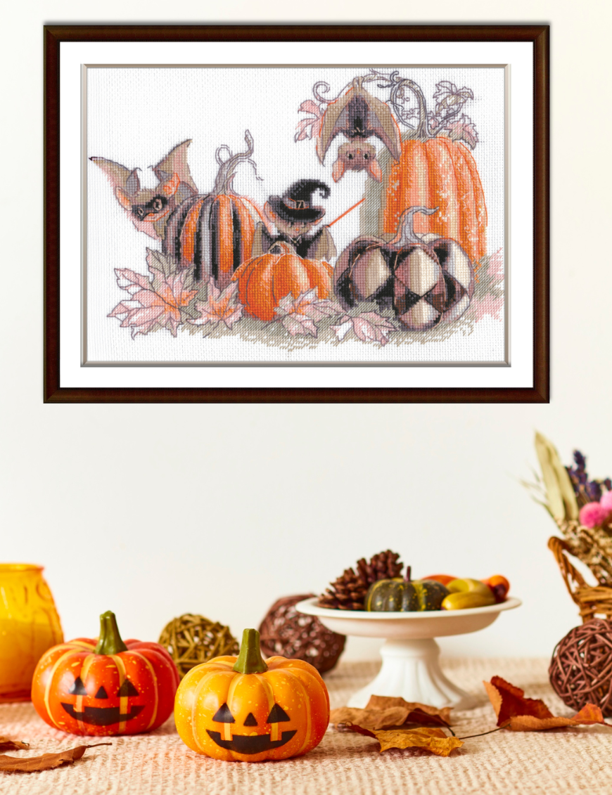 A completed cross-stitch of bats and pumpkins in a Halloween theme, with striped and checkered pumpkins, autumn leaves, and a bat in a witch hat holding a wand.