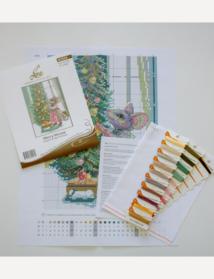 A completed cross-stitch of a mouse in a festive dress decorating a Christmas tree with ornaments, stitched in warm reds, greens, and golds on white Aida fabric.