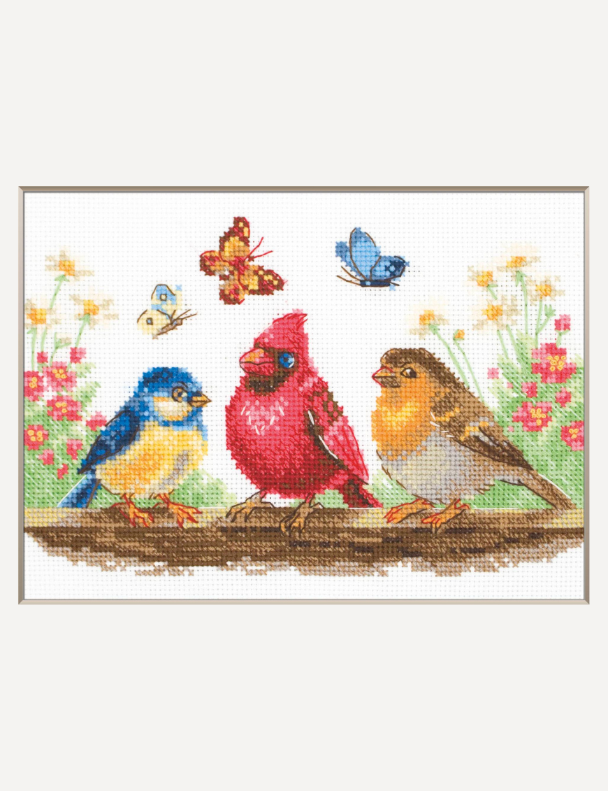 A completed cross-stitch of three colorful birds perched on a branch with butterflies and spring flowers in the background.