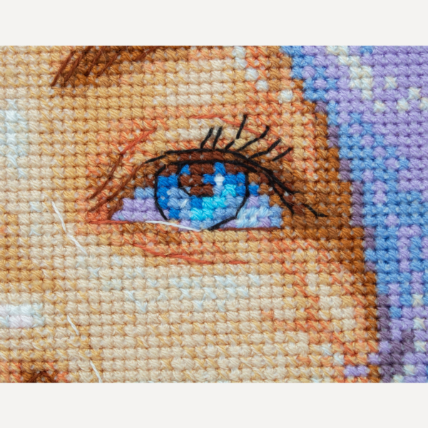 A completed cross-stitch of a girl with pastel purple hair blowing a pink bubblegum bubble, with bright blue eyes and soft blended tones.