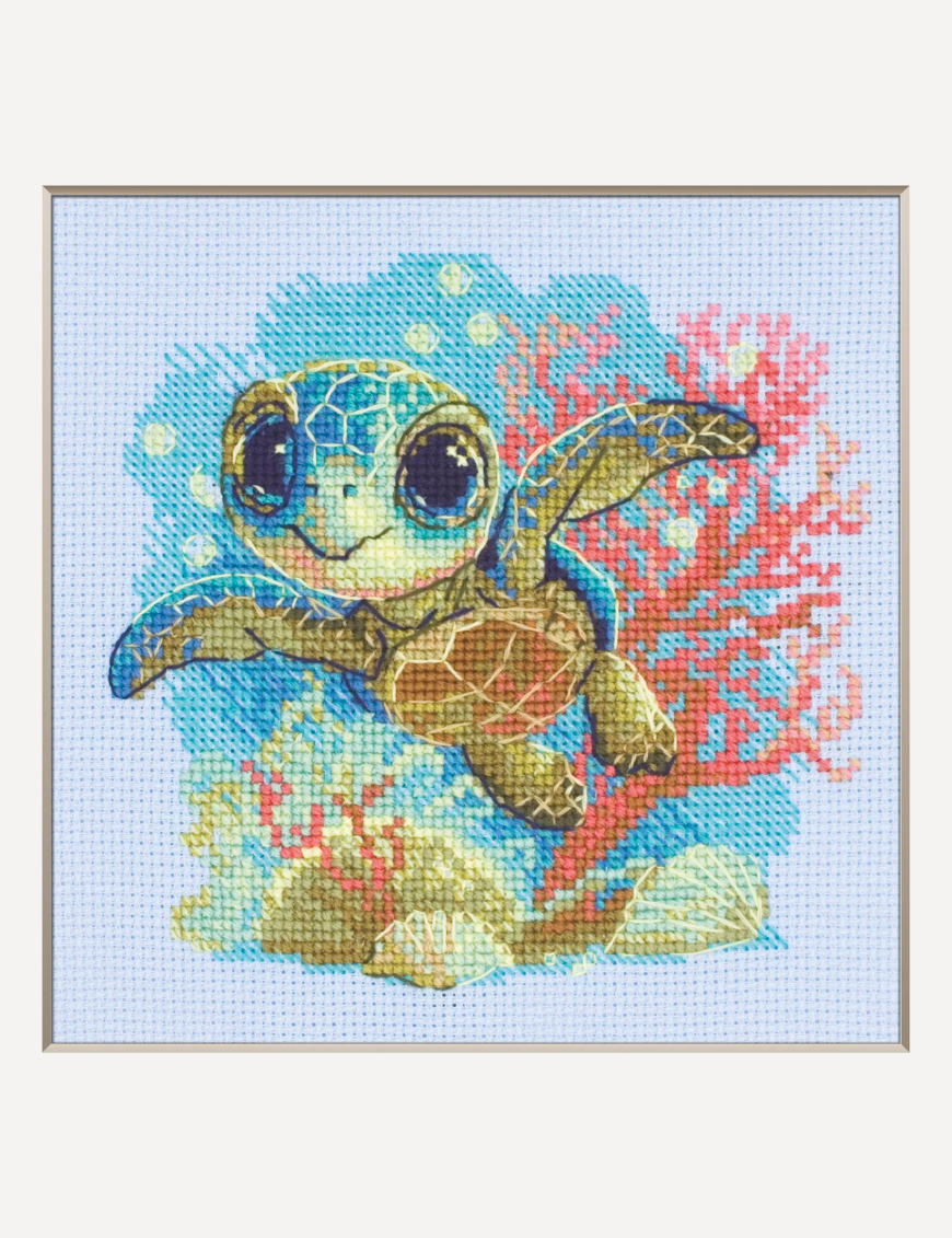 Cross-stitch kit showing a baby sea turtle underwater with coral, seashells, and a blue ocean background.