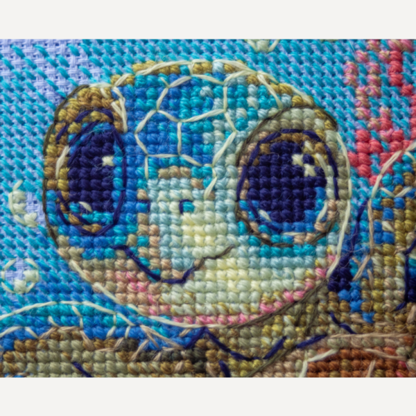 Cross-stitch kit showing a baby sea turtle underwater with coral, seashells, and a blue ocean background.