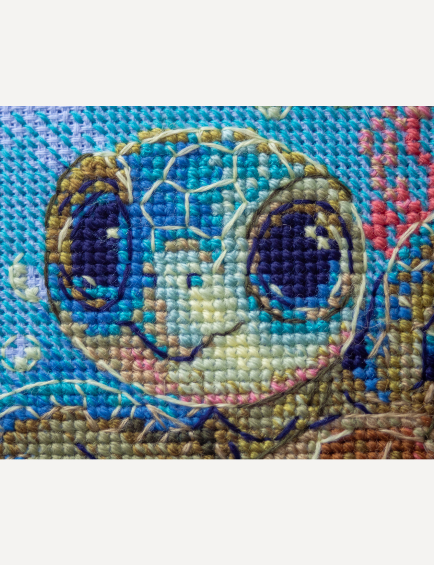 Cross-stitch kit showing a baby sea turtle underwater with coral, seashells, and a blue ocean background.