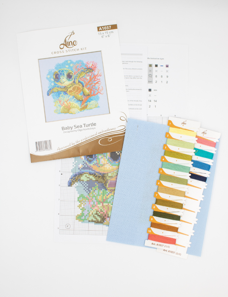 Cross-stitch kit showing a baby sea turtle underwater with coral, seashells, and a blue ocean background.