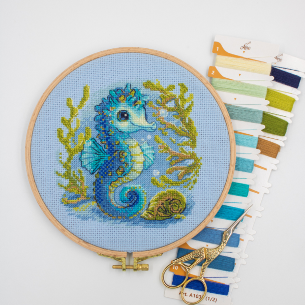 Baby Sea Horse cross stitch kit showing a blue baby seahorse underwater with golden seaweed and a shell.