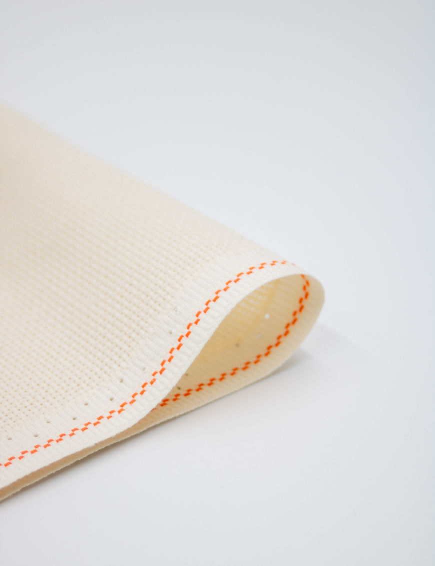 Close-up of Zweigart cream Aida fabric showcasing its intermediate evenweave grid and warm, soft cream color.