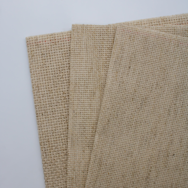 Close-up of Zweigart 10 count Rustico Aida fabric showcasing its easy-to-stitch evenweave grid and natural, earthy flecked appearance.