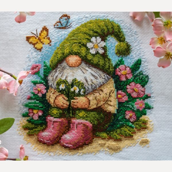 A1042 Blossom Gnome Aine Cross-Stitch Kit featuring a garden gnome in a green hat surrounded by pink flowers, foliage, and butterflies.