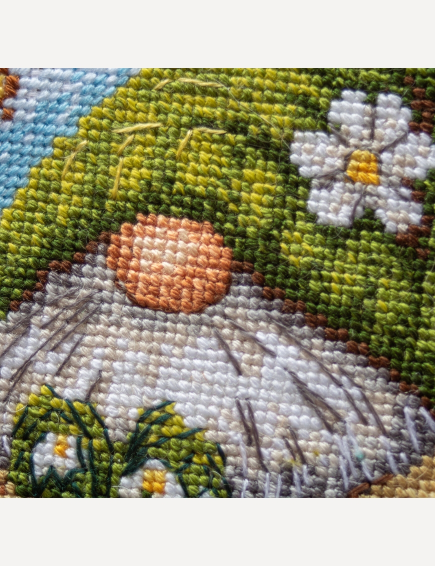 A1042 Blossom Gnome Aine Cross-Stitch Kit featuring a garden gnome in a green hat surrounded by pink flowers, foliage, and butterflies.