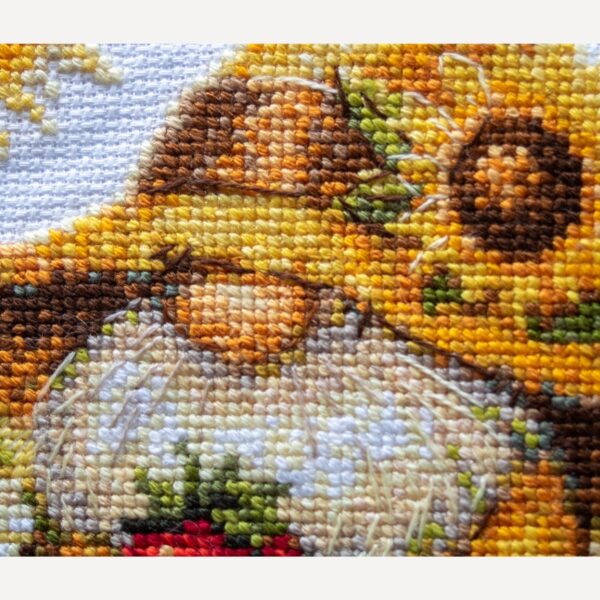 A1043 Sunshine Gnome Aine Cross-Stitch Kit featuring a garden gnome in a yellow sunflower hat surrounded by red flowers, daisies, and green foliage.