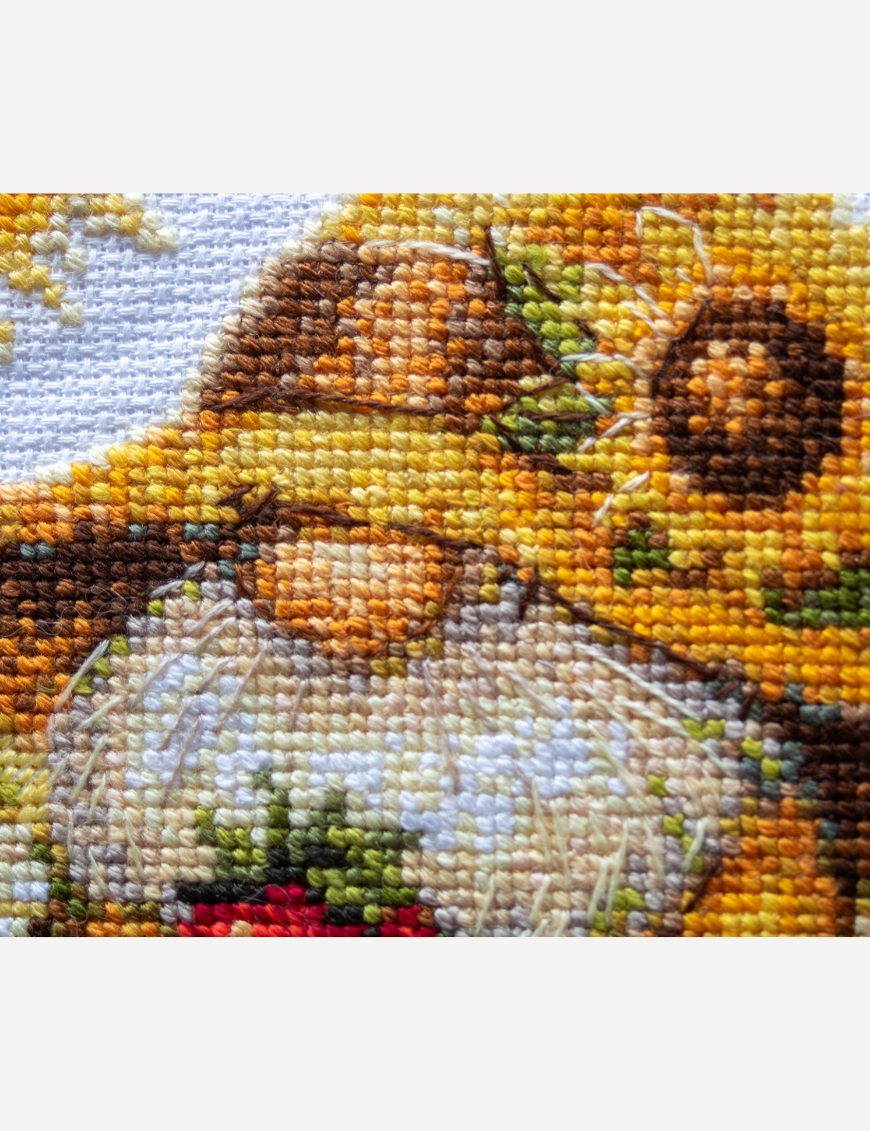 A1043 Sunshine Gnome Aine Cross-Stitch Kit featuring a garden gnome in a yellow sunflower hat surrounded by red flowers, daisies, and green foliage.