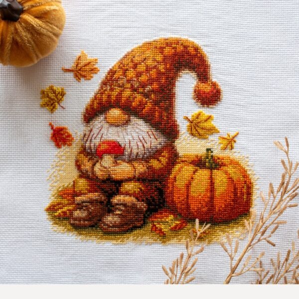 A1044 Harvest Gnome Aine Cross-Stitch Kit featuring an autumn gnome with a large orange pumpkin, colorful fall leaves, and a tiny red mushroom.