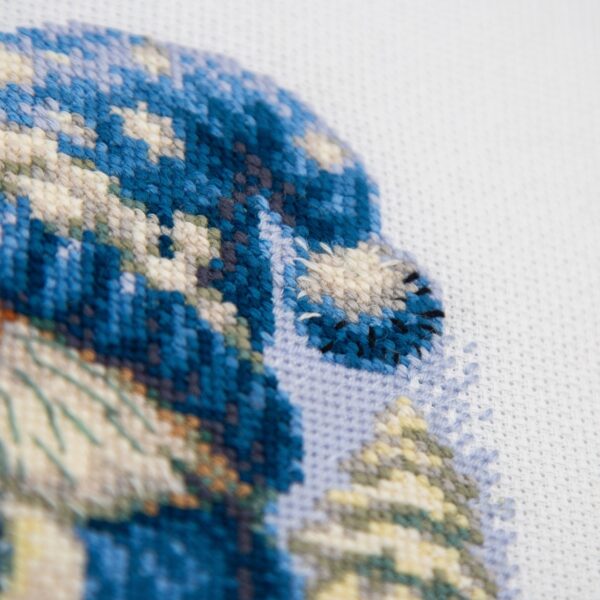 A1045 Snowy Gnome Aine Cross-Stitch Kit featuring a winter gnome with a blue snowy hat, glowing lantern, wooden sled, bird, and snow-covered evergreen trees.