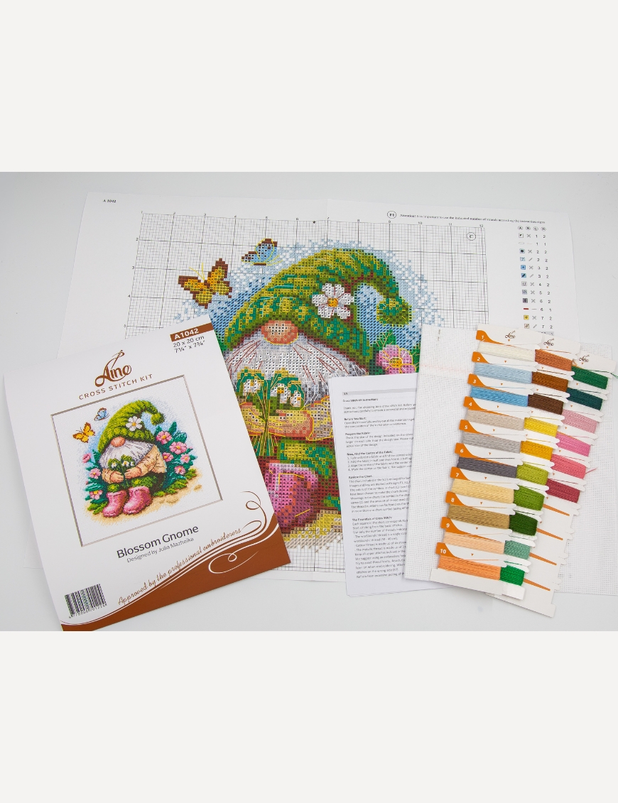 A1042 Blossom Gnome Aine Cross-Stitch Kit featuring a garden gnome in a green hat surrounded by pink flowers, foliage, and butterflies.