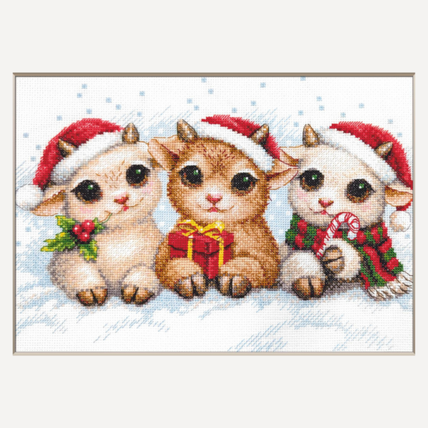 A completed cross-stitch picture of three baby goats wearing red Santa hats, huddled together in falling snow: one with a sprig of holly and red berries, one holding a wrapped Christmas present with a red bow, and one wearing a red-and-green plaid scarf and holding a candy cane.