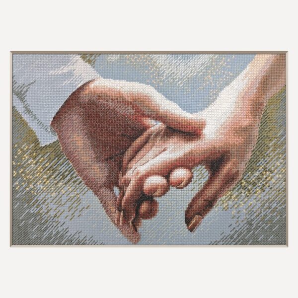 A completed cross-stitch picture of two hands gently clasped together, one in a white shirt cuff, against a soft blue-grey background with golden sparkles.